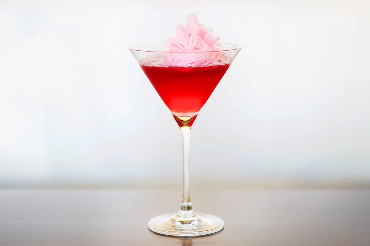 A vodka martini cocktail topped with pink cotton candy