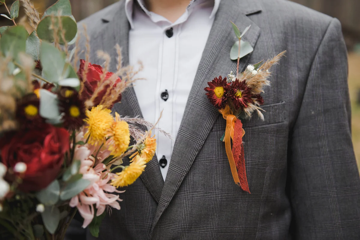 Autumn wedding, the groom holds a bouquet waring boho bouttonniere