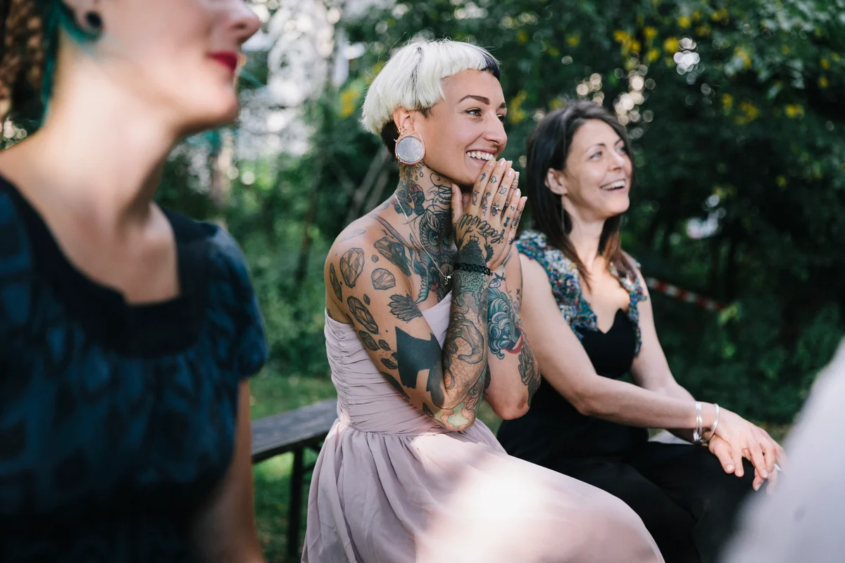 Tattooed wedding guest clasping her hands together