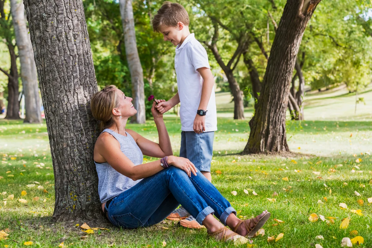 Mom wearing jeans and a comfortable top while playing in the park with her son