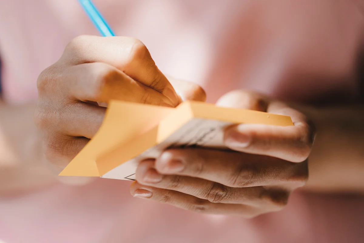 Woman writing with pen on adhesive notes