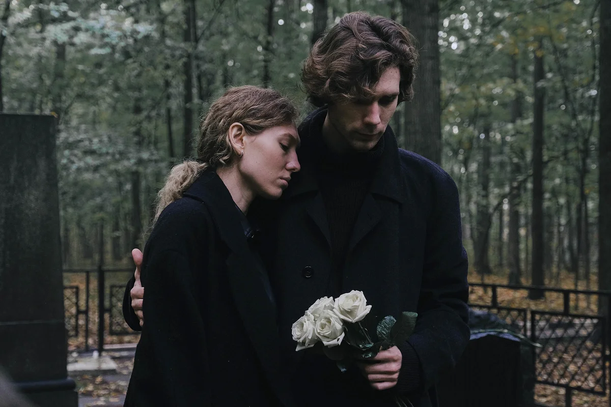 man and woman mourn at the cemetery for the loss
