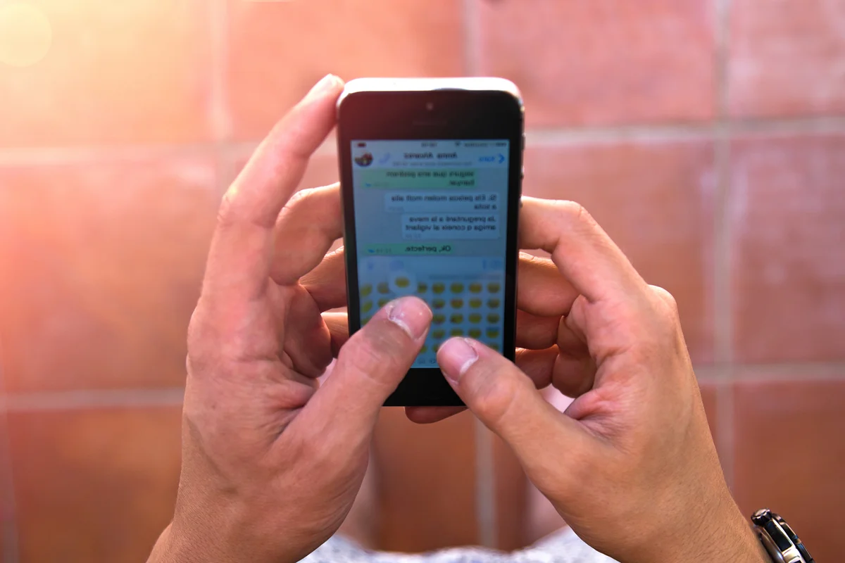 Guy texting with smartphone from personal point of view sending emojis