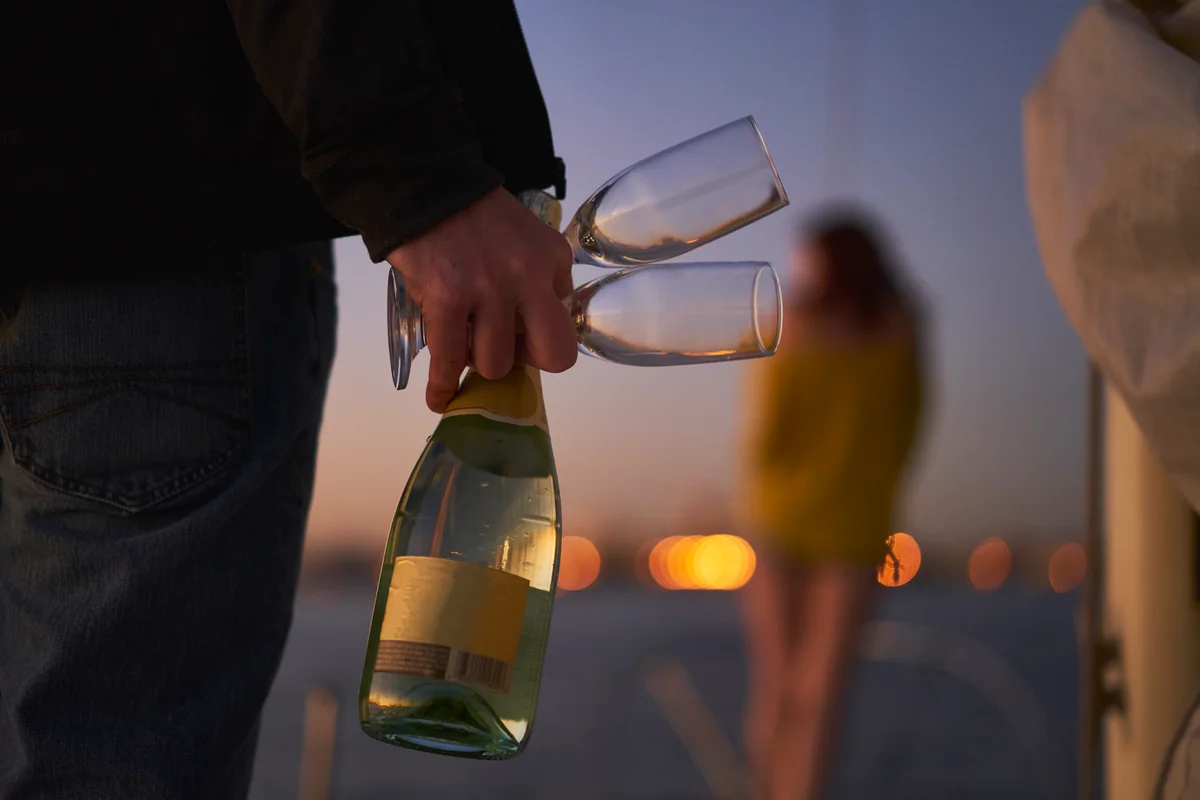 man holding a champagne bottle and glasses