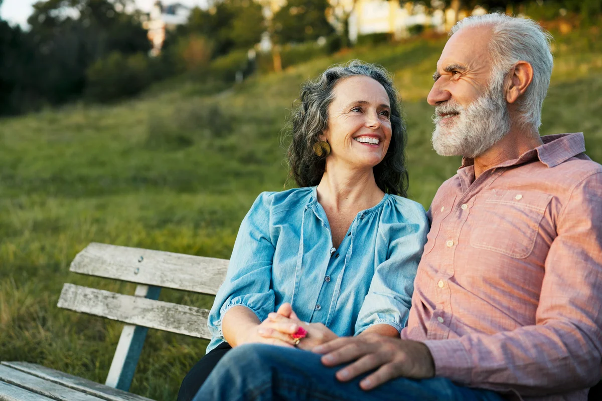 Man and woman smiling and sitting on a bench