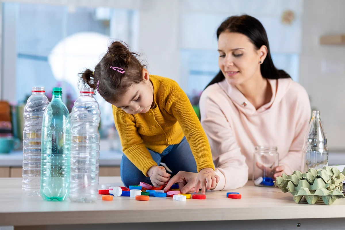 Mother teaching her daughter how to recycle waste.