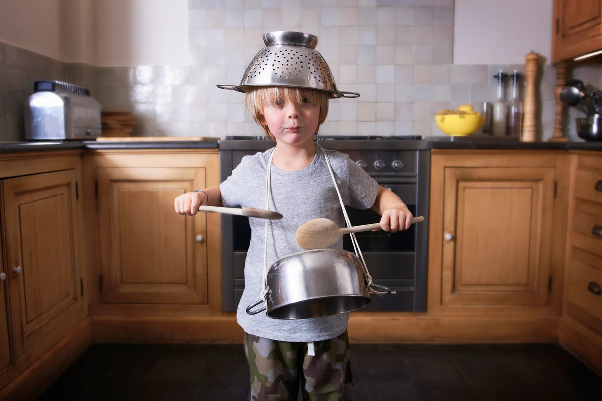 Boy playing the drums on a pan with spatulas
