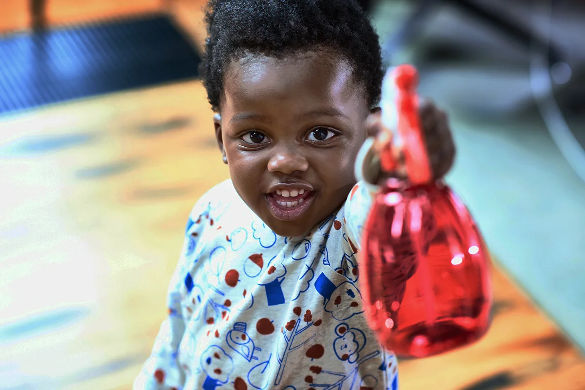 Cute toddler holding spray bottle and smiling