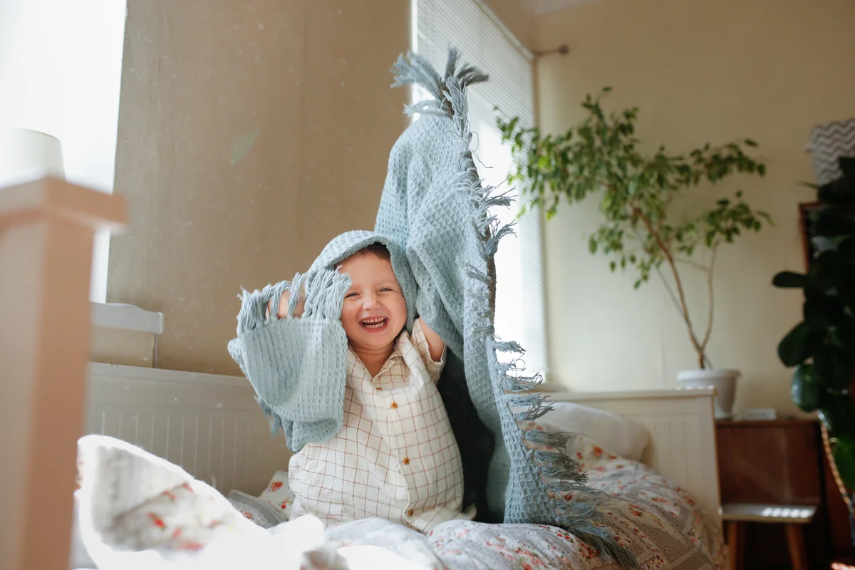 kid playing hide and seek under blanket