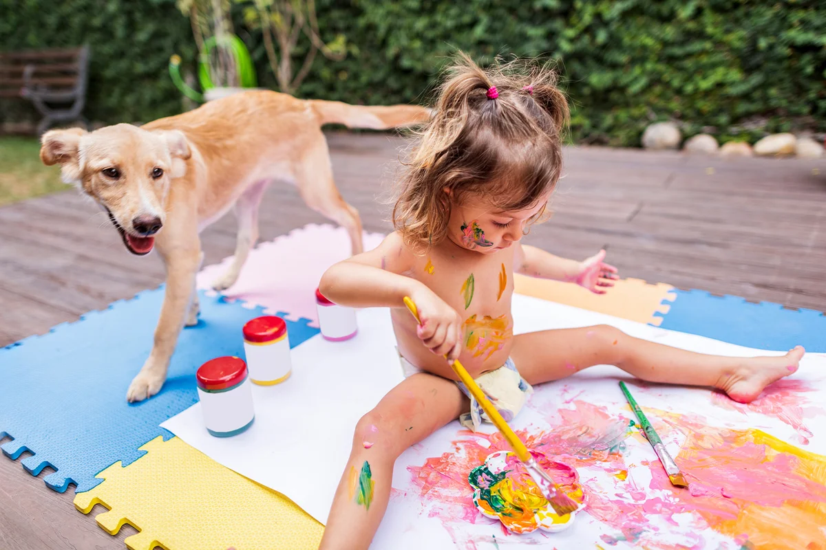 Cheerful little girl have fun with acrylic paint on a summer day