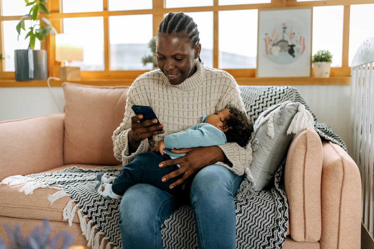 mom holding sleeping baby on phone