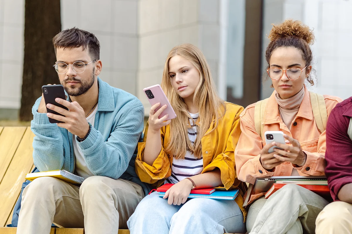 Group of students sitting together and using their smart phones