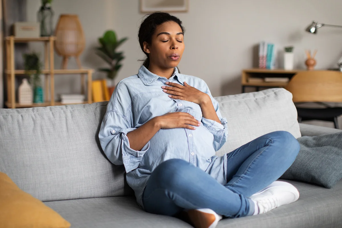 Pregnant Woman Doing Breathing Exercise Sitting At Home
