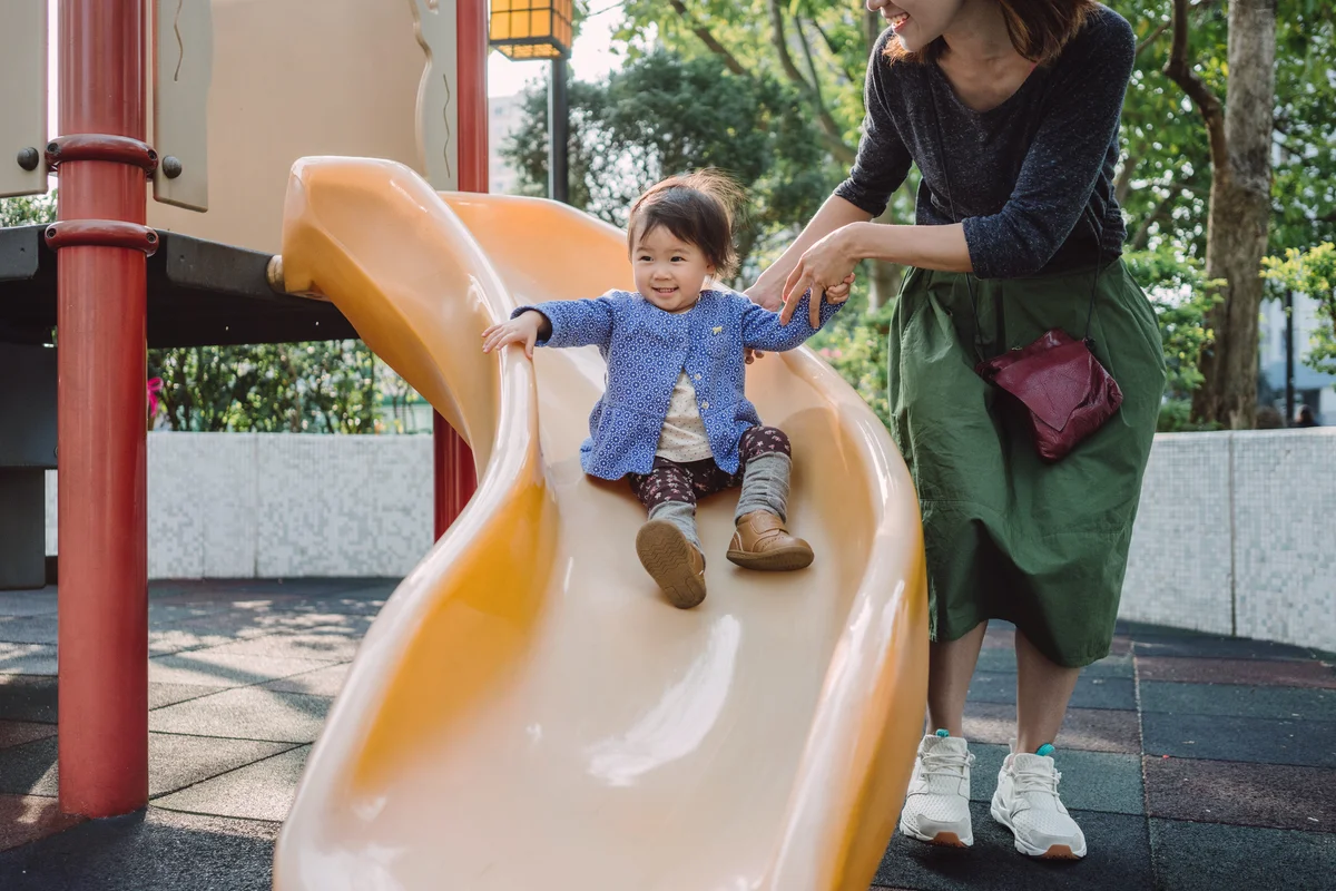 Mom and baby playing slide in playground