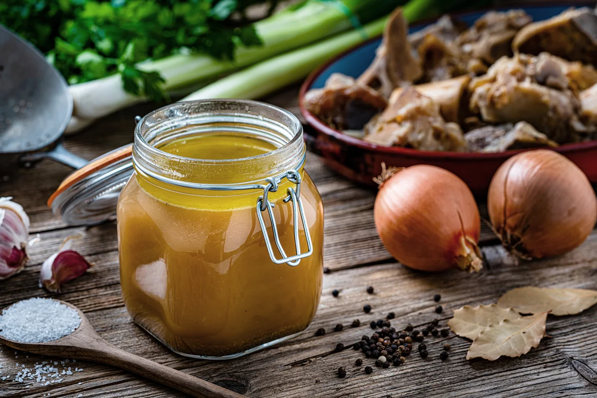 Bone broth in a glass jar on rustic table