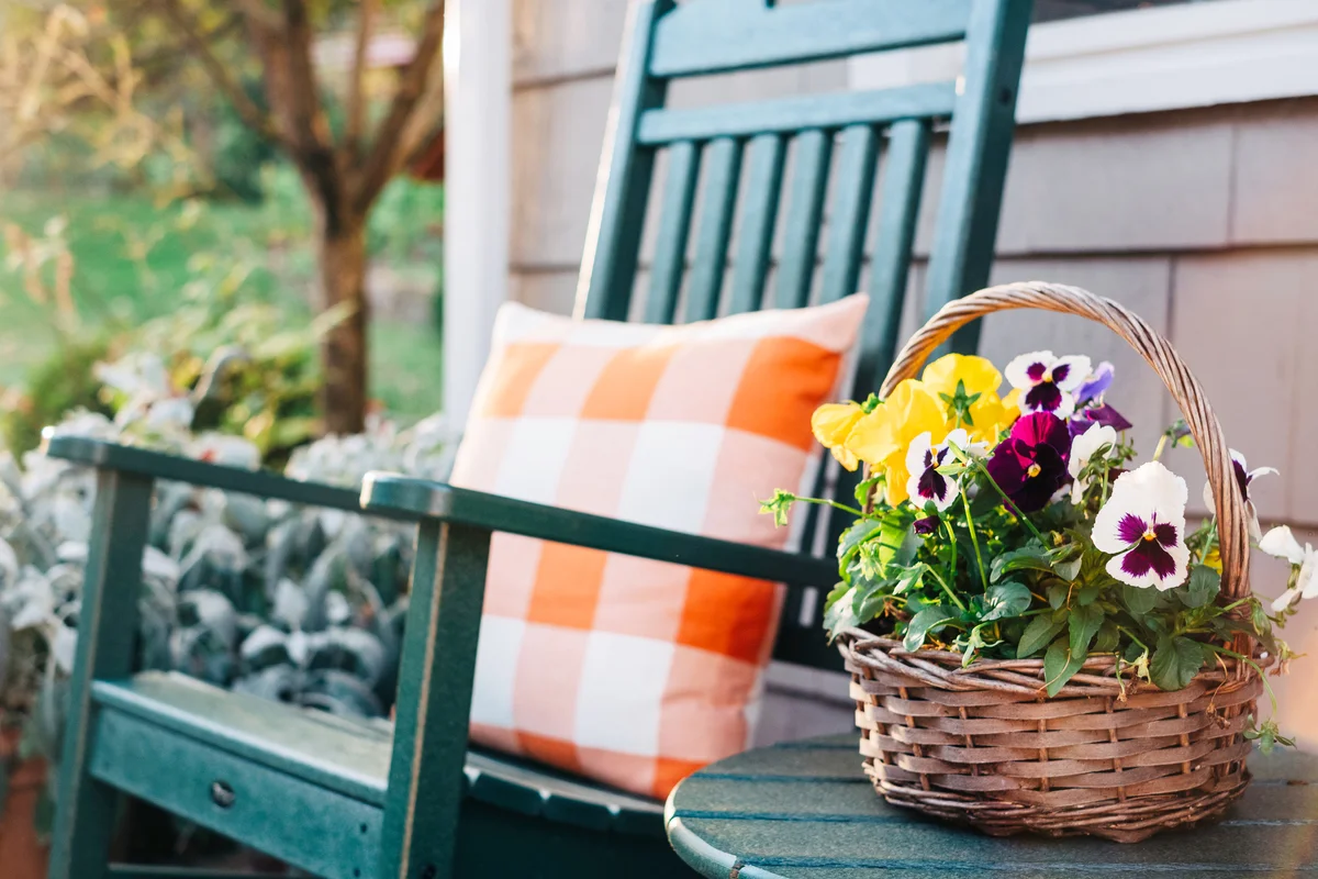 Flower basket next to a green rocking chair