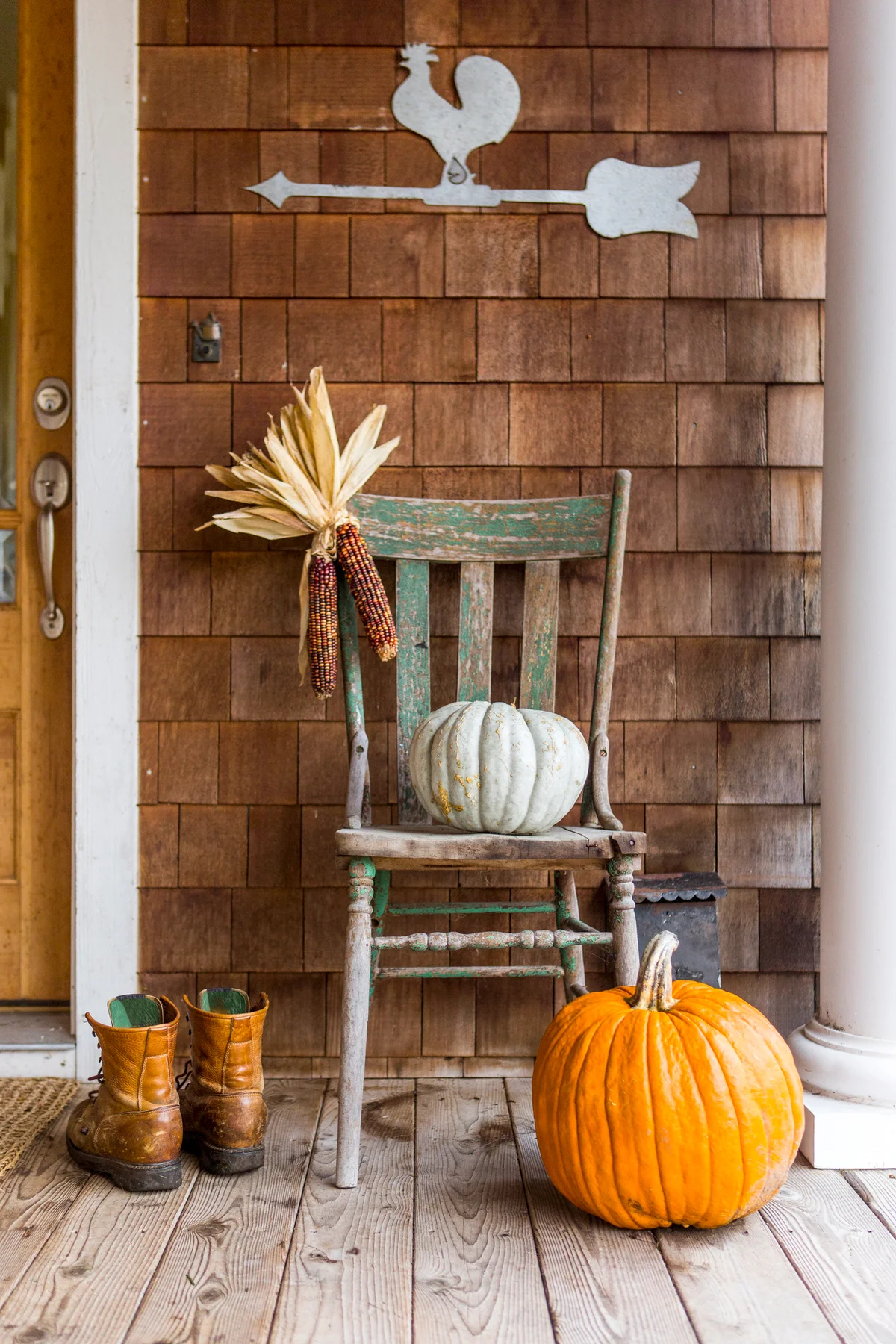 Pumpkins and corn on porch with boots in autumn