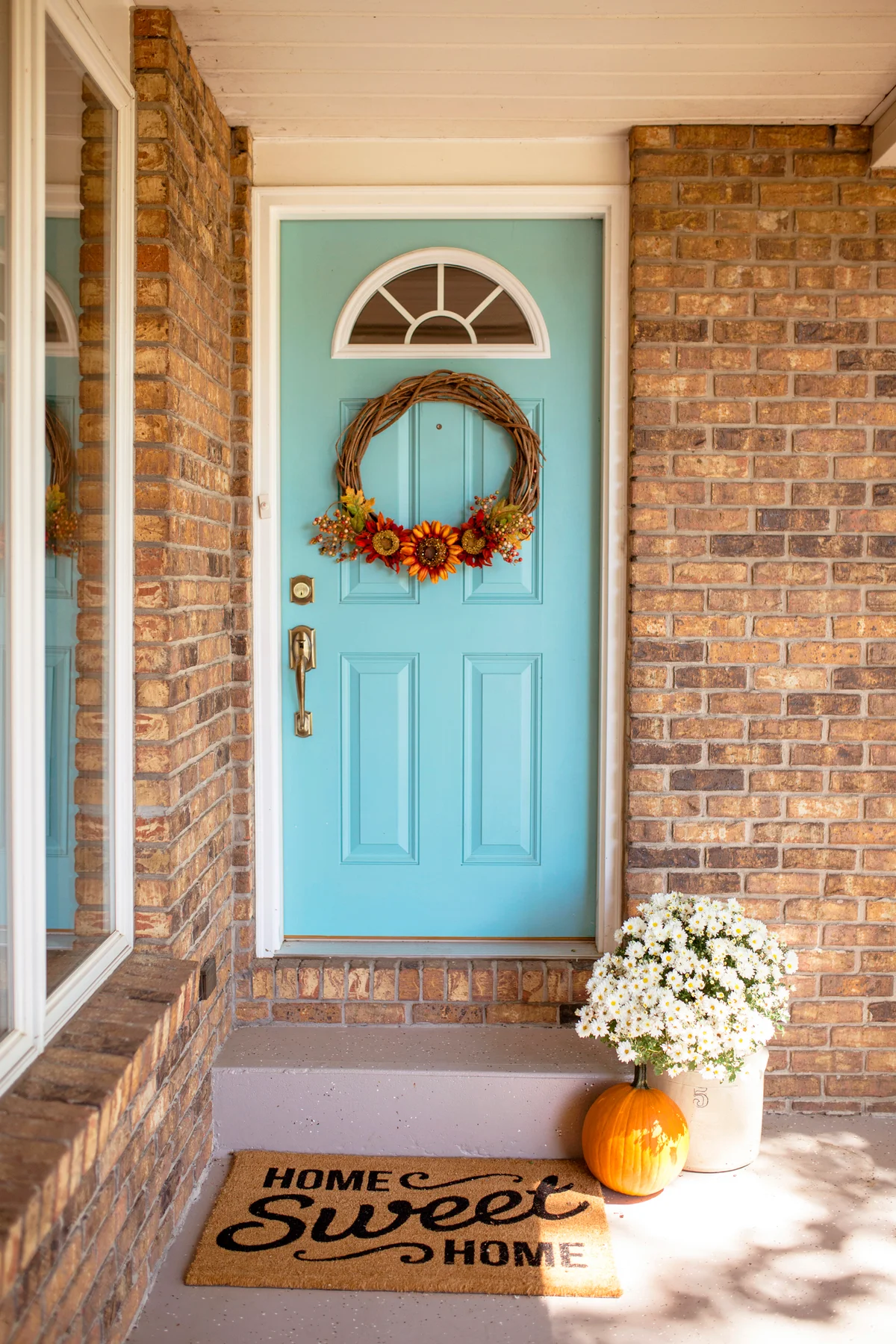 Wreath hanging on door with pumpkin in front of house