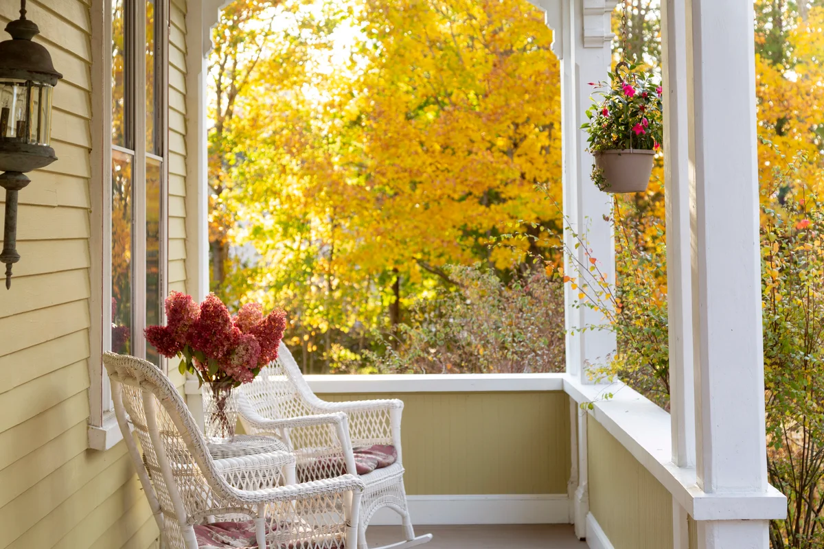 Front Porch of Home with Wicker Chairs with Autumn Trees