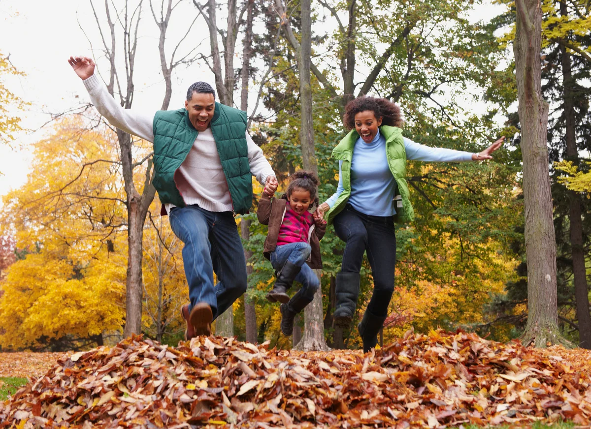 Family jumping in a pile of leaves