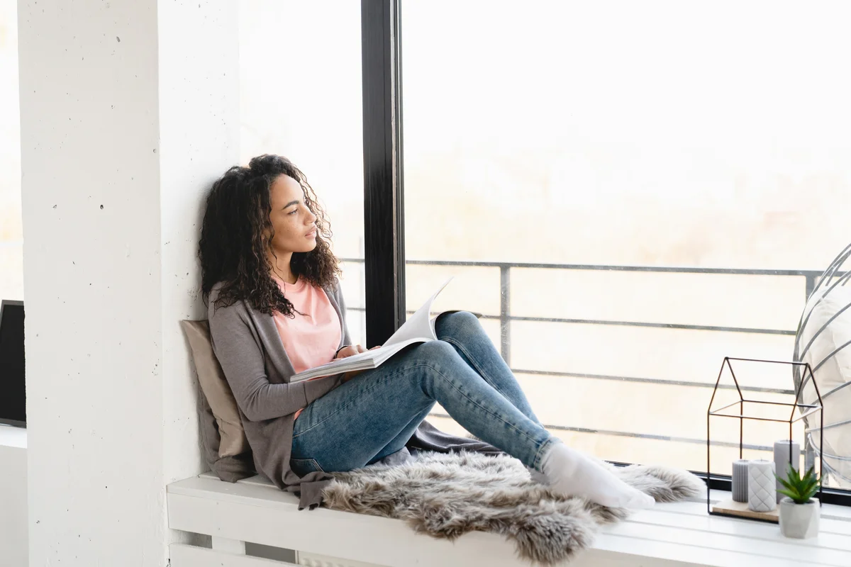 woman on window seat reading a book