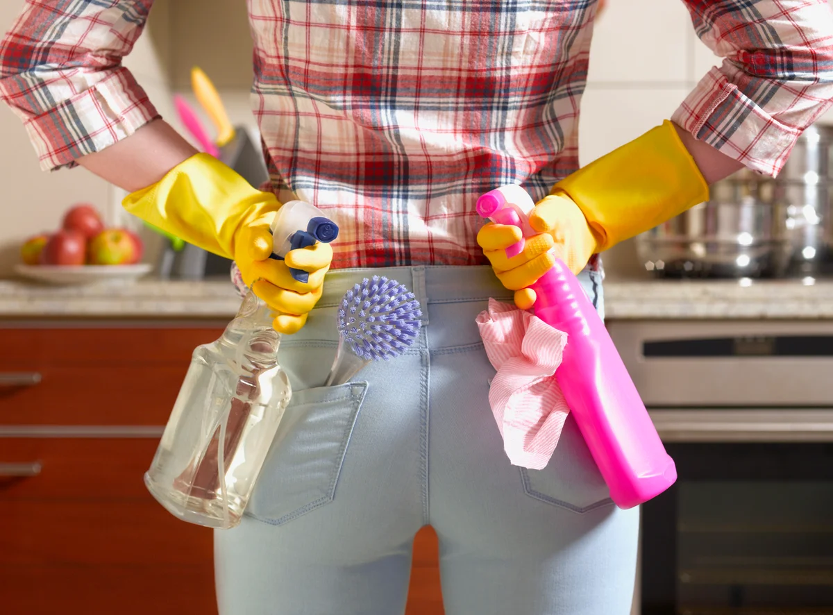 woman holding cleaning supplies behind her back