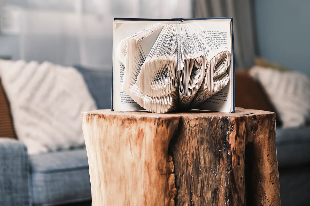A book with the word love is on a table shaped like a tree trunk