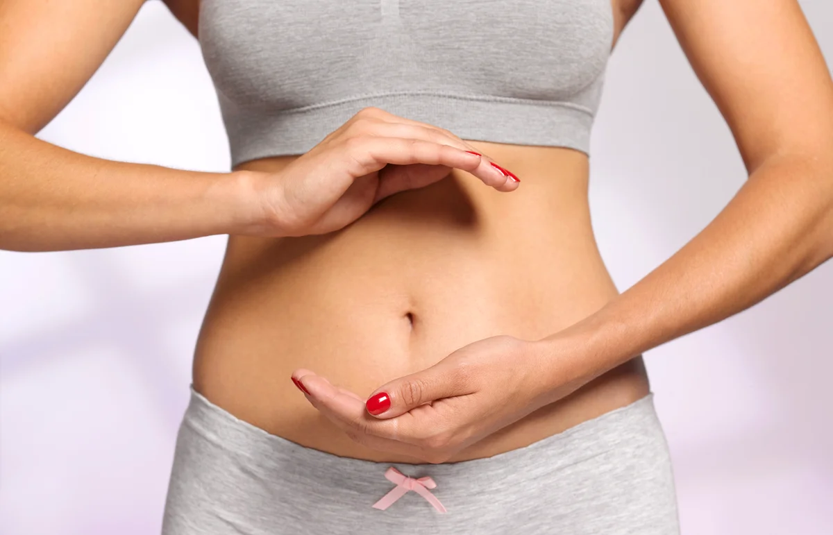 Woman holding hands around belly button