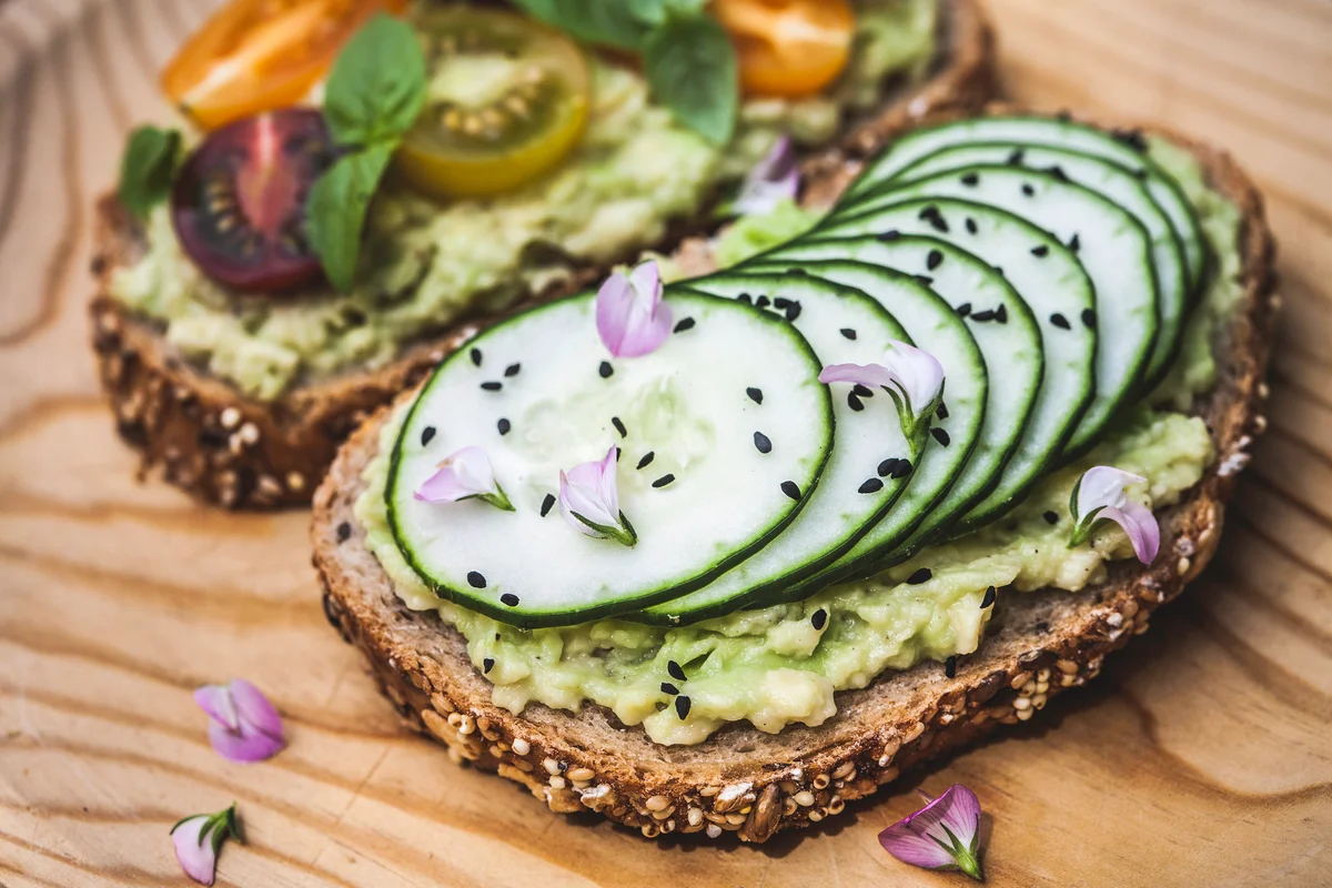 Avocado toast topped with tomatoes and cucumber