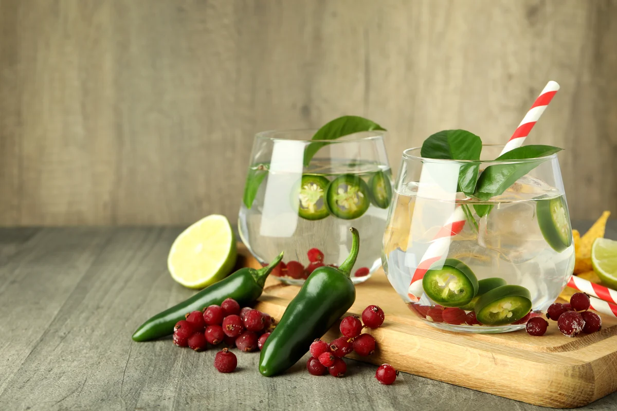 Clear cocktail with jalapenos and berries