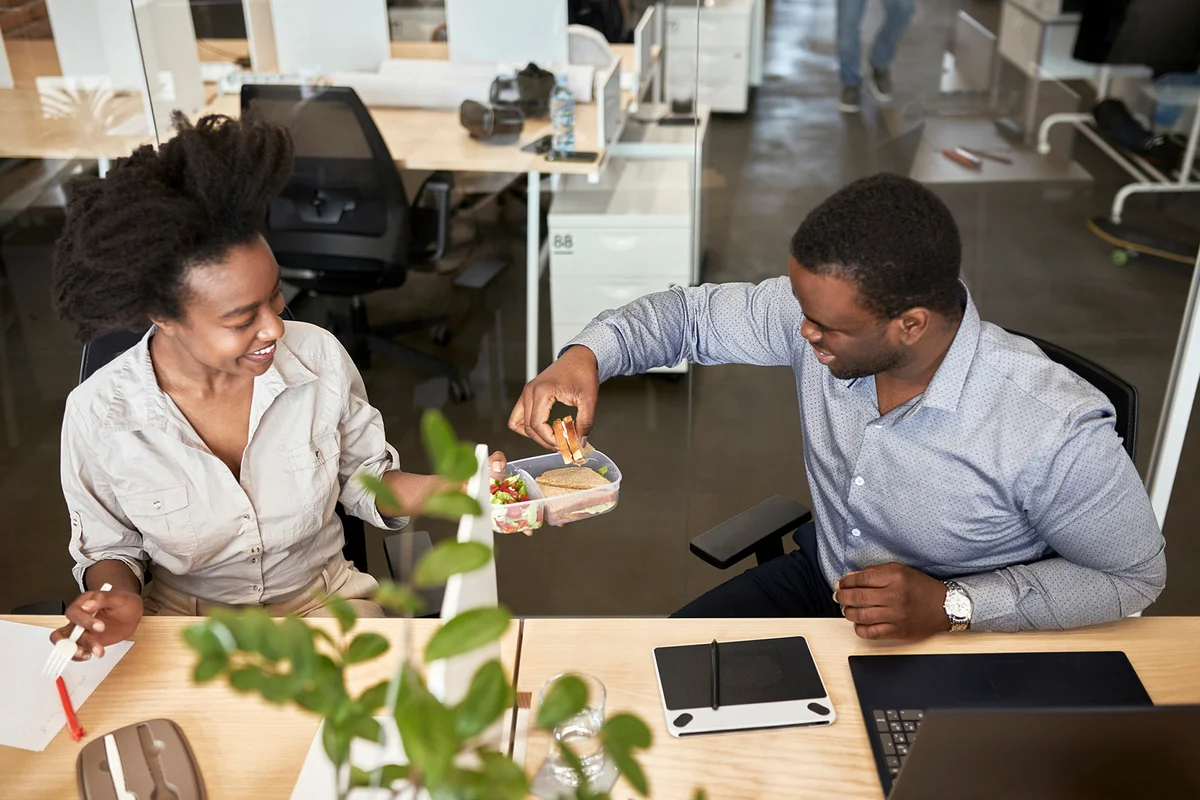 coworkers sharing sandwiches during lunch break at coworking office
