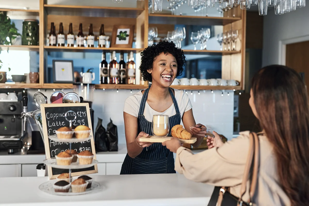 young woman accepting a credit card payment while serving a customer in a cafe