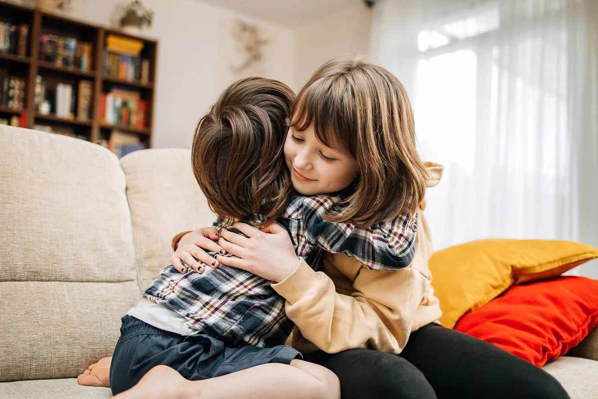 The little brother hugs his sister and laughs