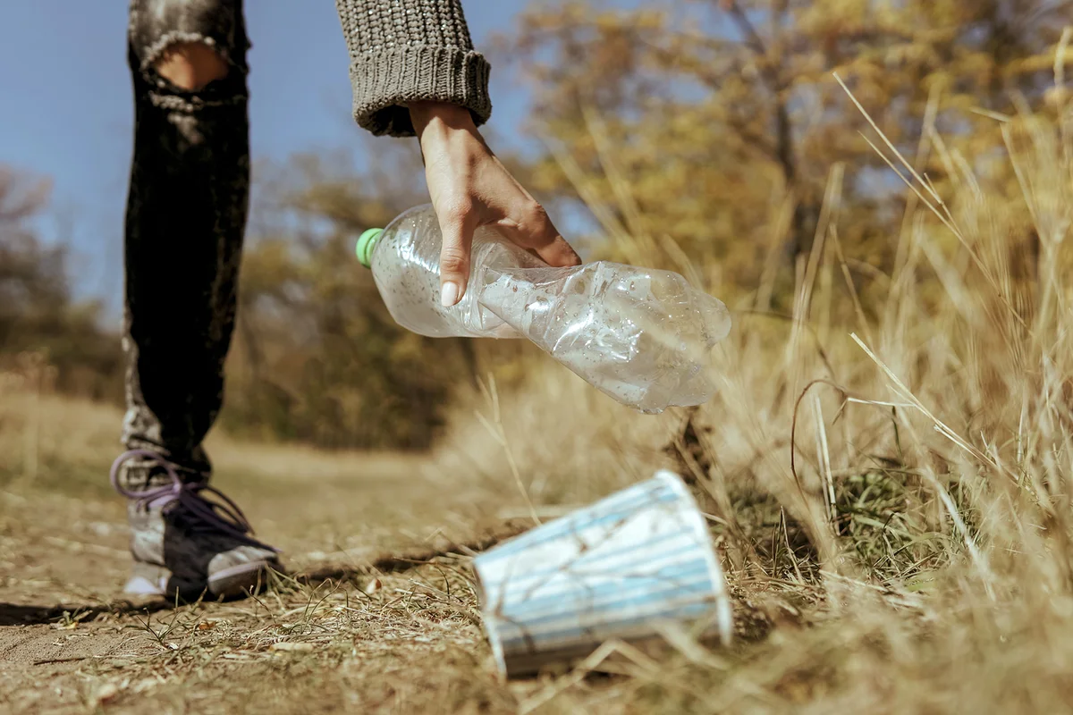 Hand woman picking up plastic bottle cleaning in the street