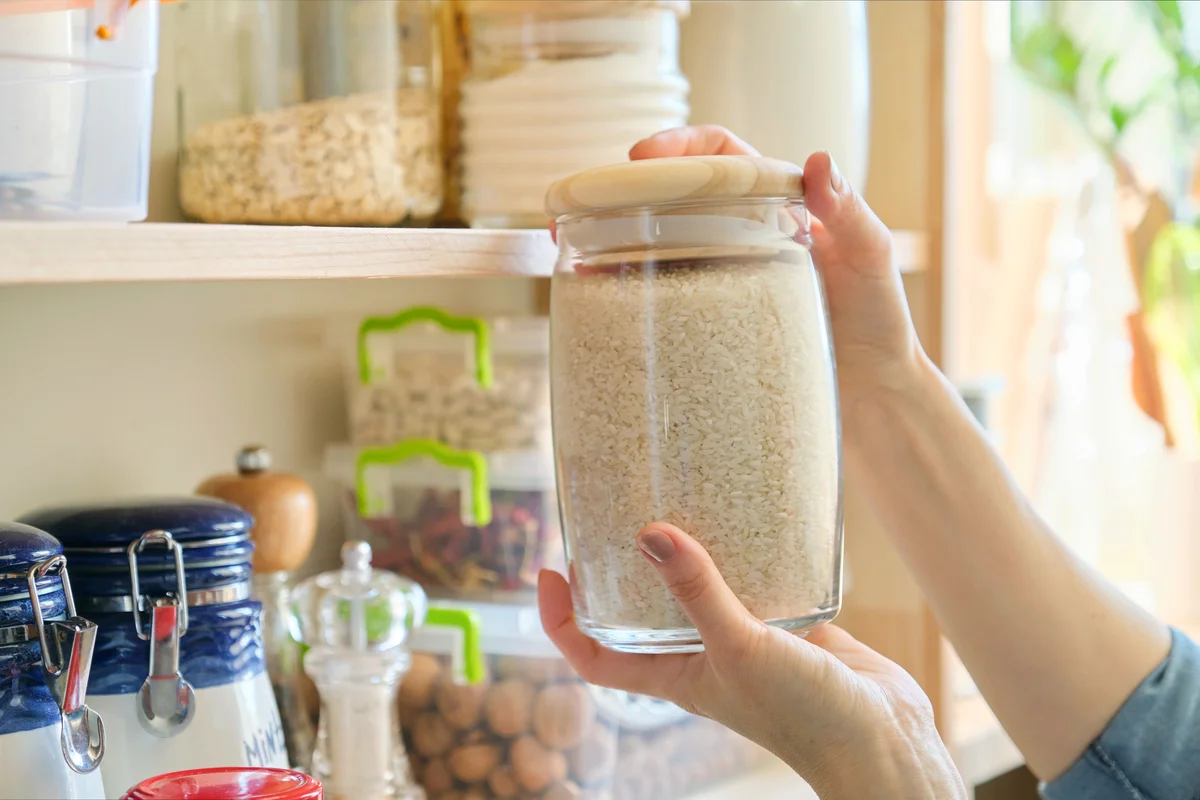 Woman holding a jar of rice in kitchen pantry