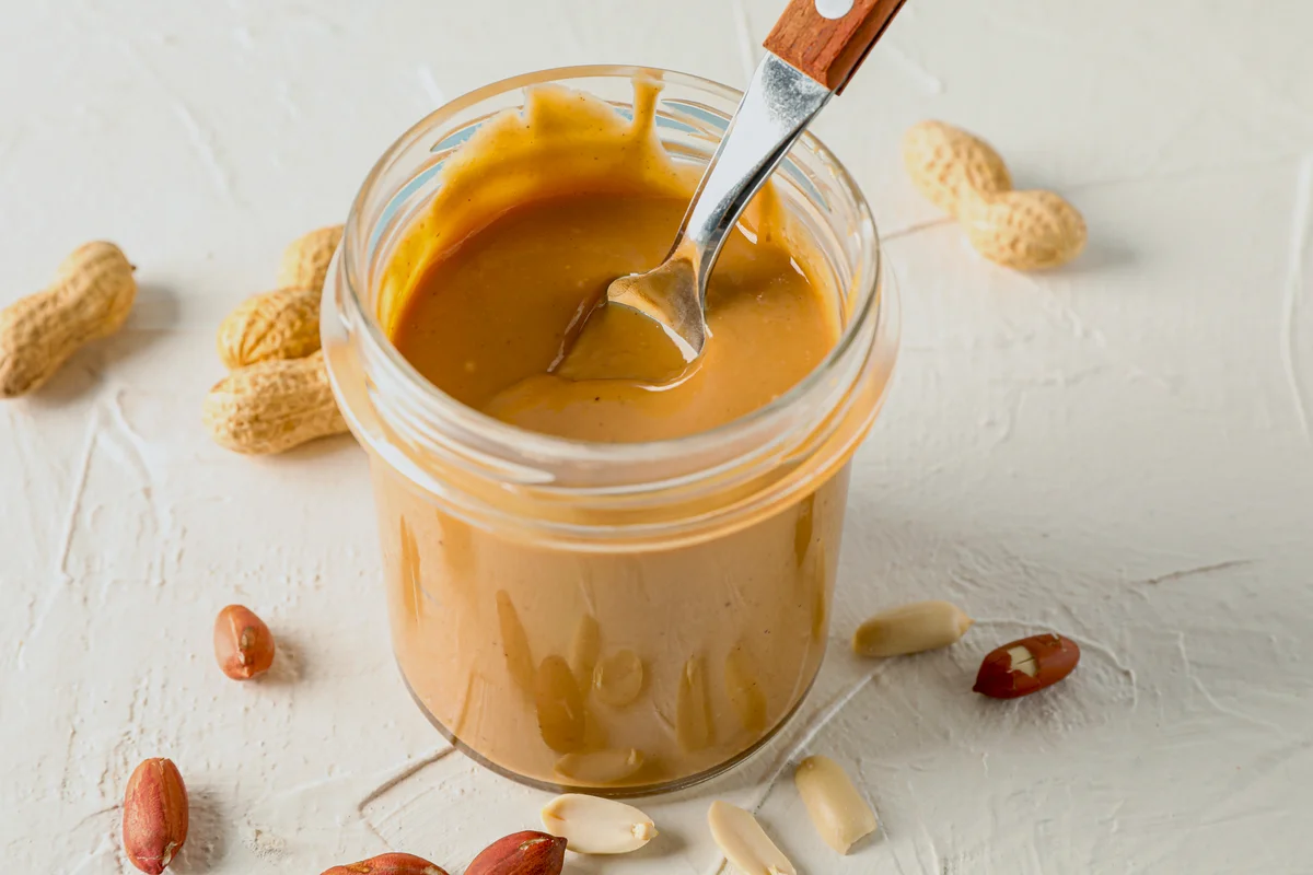Glass jar with creamy peanut butter and spoon