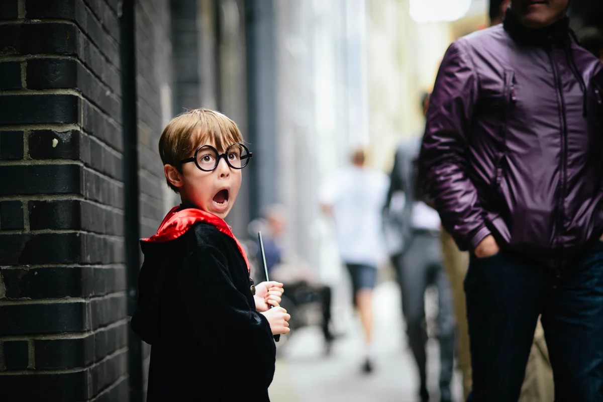 A little boy dressed like Harry Potter, looking scared