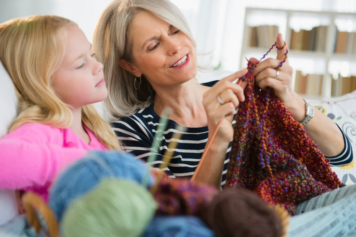 Woman and granddaughter knitting on sofa