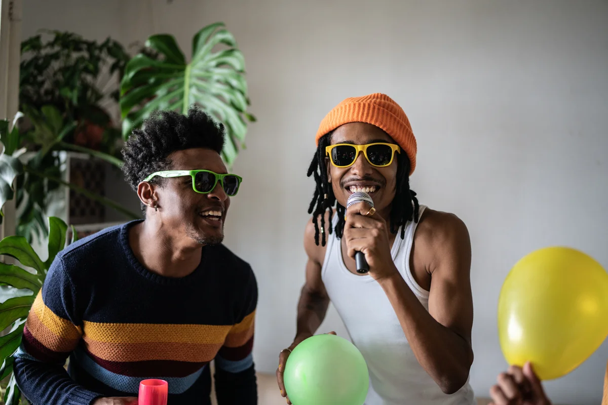 Guy friends having fun singing at party