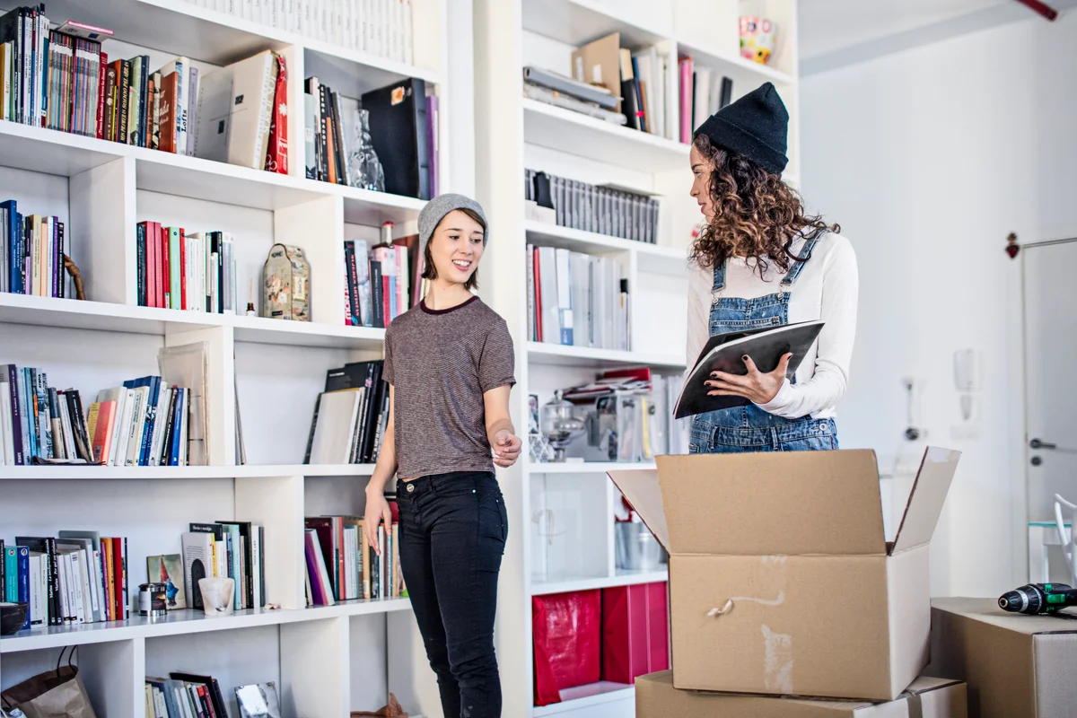 Two women organized bookshelves