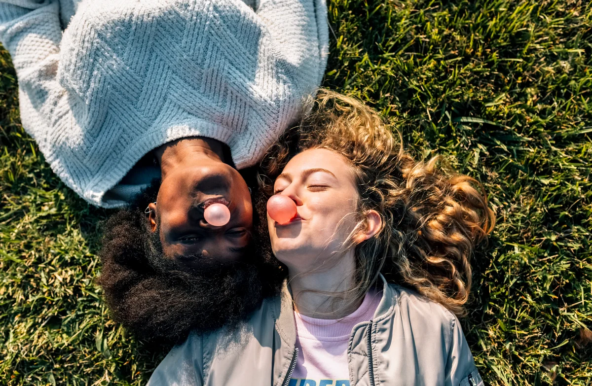 friends laying in the grass blowing bubblegum