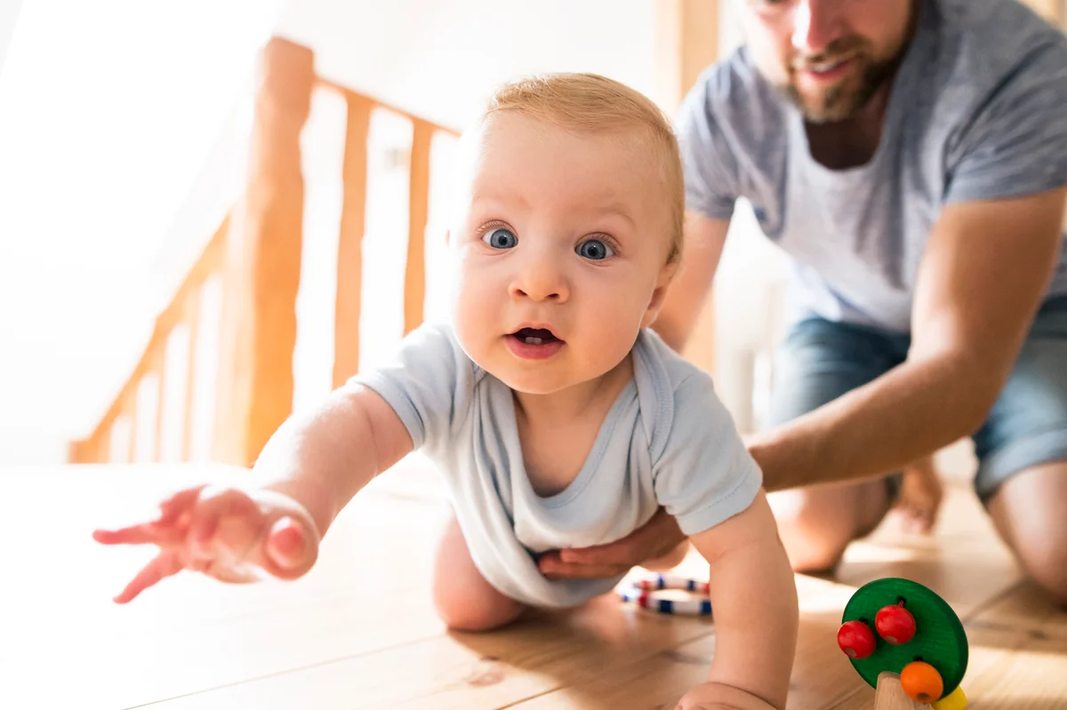 Dad helping baby crawl