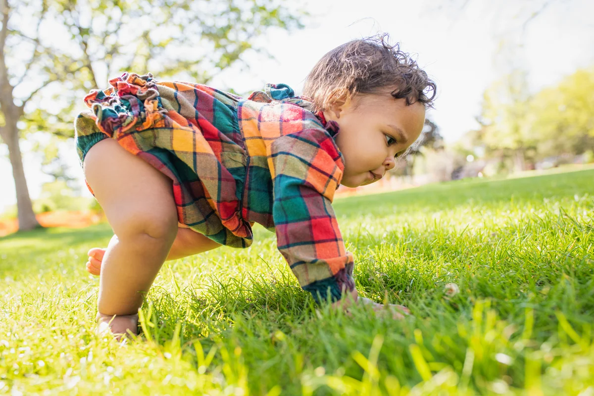 Baby girl crawling in grass