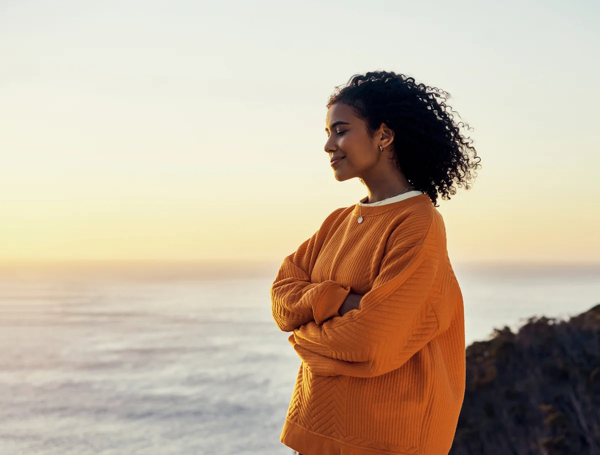 Woman at peace while watching sunset at water