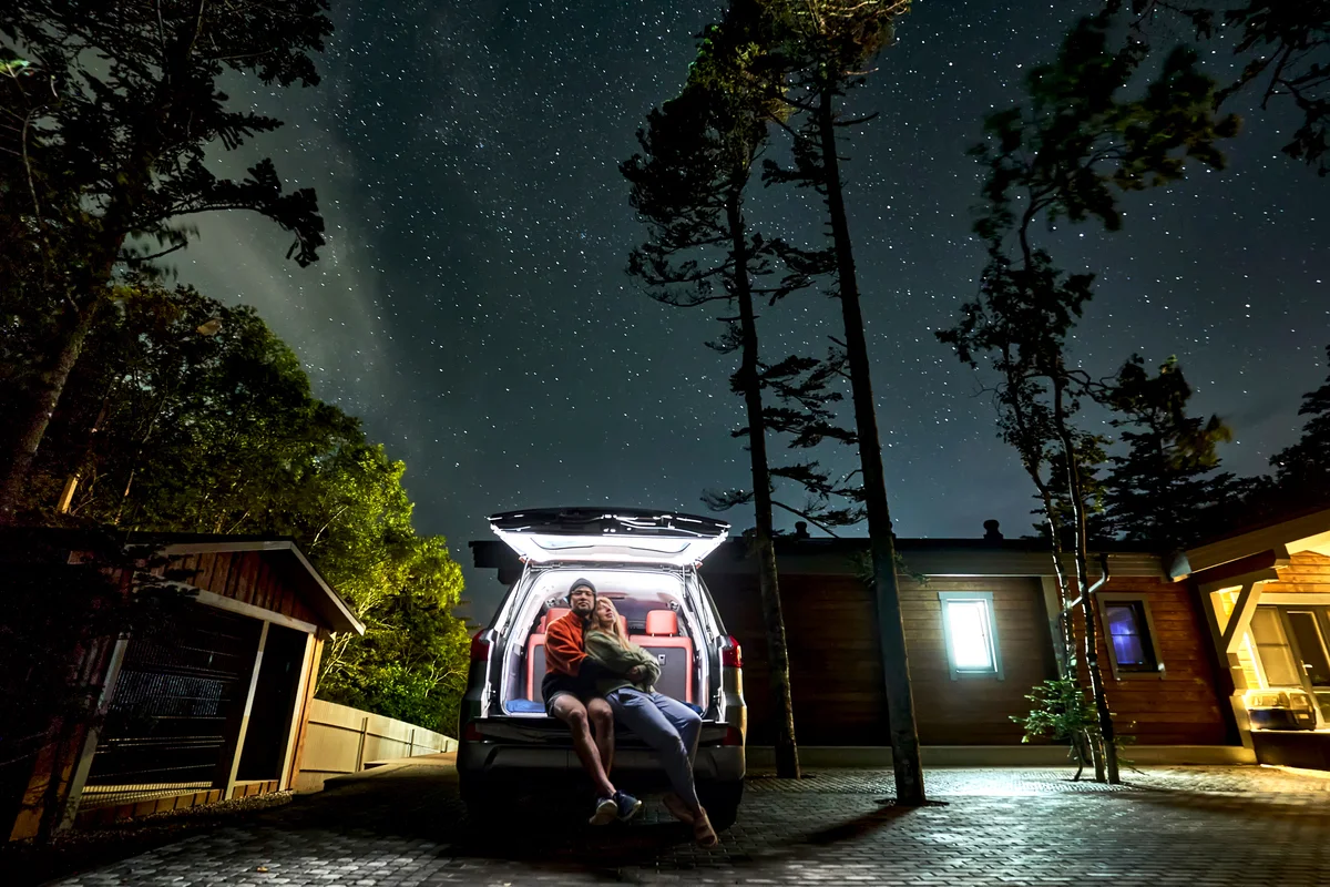 Couple stargazing from their car at night