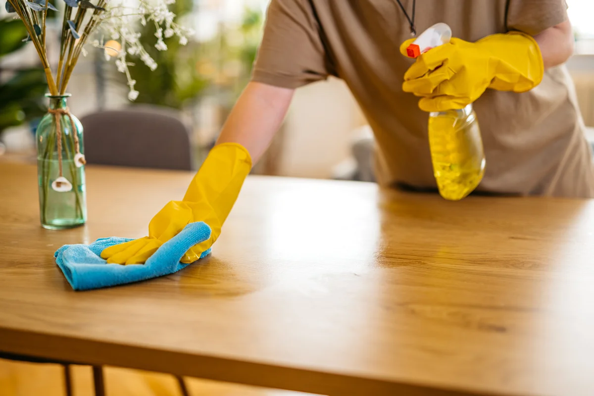 Woman cleaning table with microfiber cloth