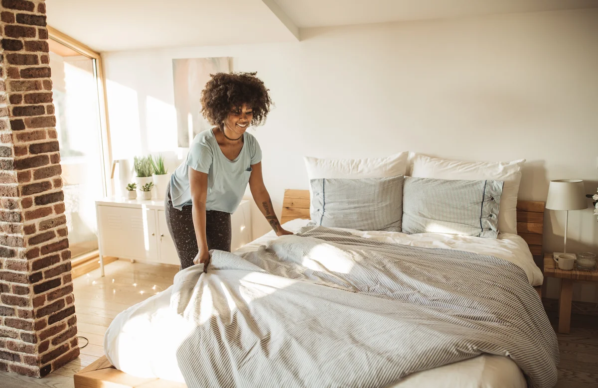 Woman making her bed with fresh bedding