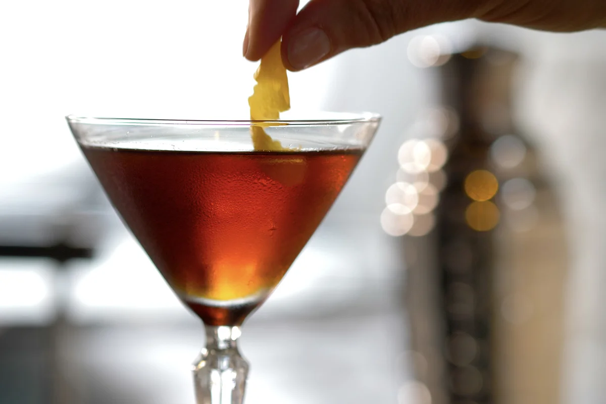 Cocktail Being Finished With a Lemon Twist