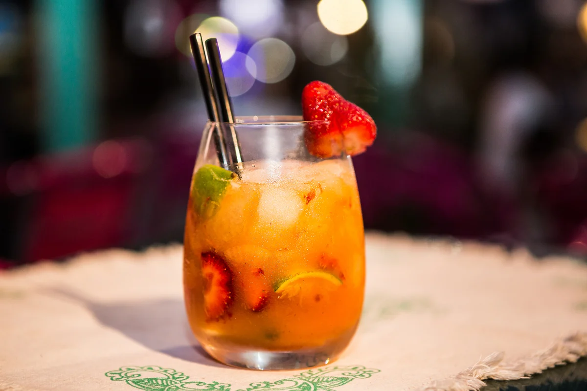 Hooting for peaches cocktail garnished with strawberries and lime
