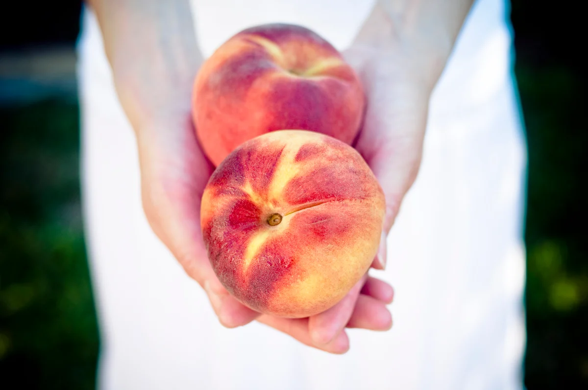 Woman holding two peaches